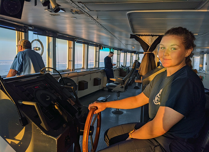 Navigation Cadet Breanna Bell steers the ship through the river in the ocean.