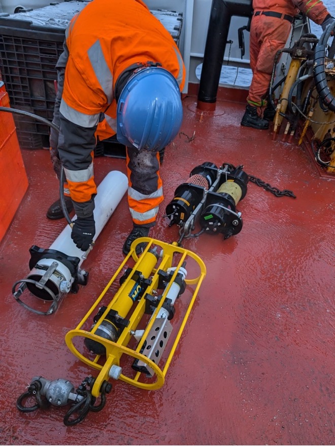 Tim McDonough gives the upward looking sonar a freshwater wash after its year spent in the Beaufort Sea recording ice draft (Photo by Mary-Louise Timmermans)