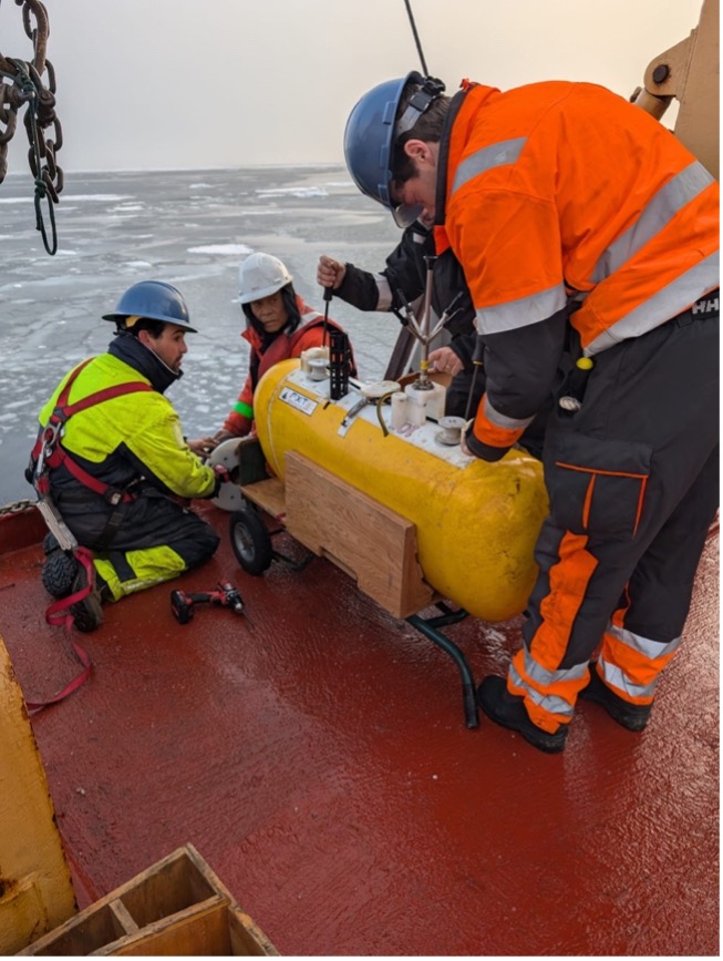 Bosun Rico Amamio and the WHOI team take the MMP off the mooring wire.