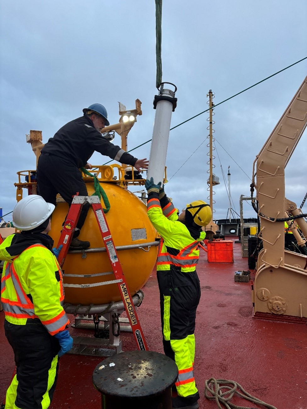 Photo 3: WHOI engineer Jeff O’Brien handing CCG cadet Adelaide Paquet the recovered upward looking sonar (ULS) from Mooring D. 