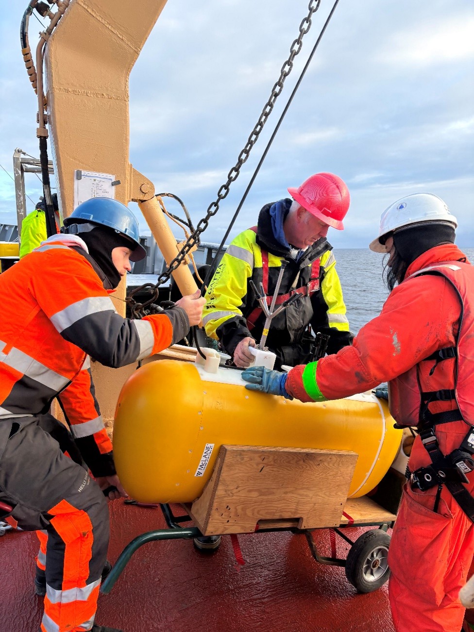 Photo 3: Tim McDonough (left), Jim Ryder (middle), and boatswain Rico Amamio (right) attaching a McClane Moored Profiler (MMP) to the mooring wire.  