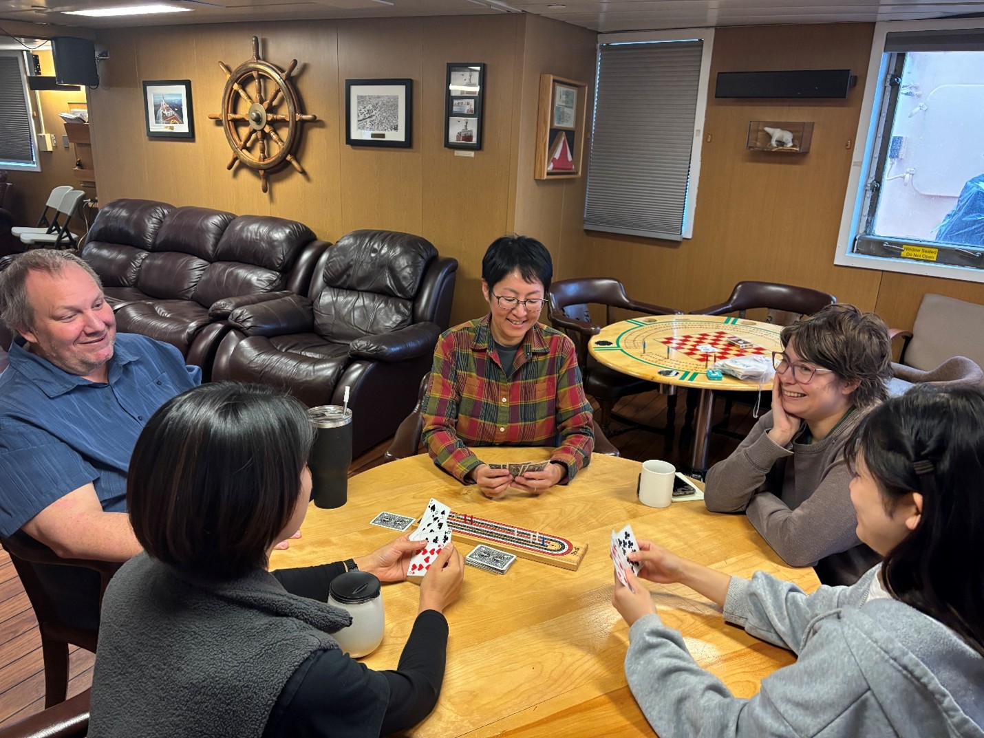 Photo 5: Members of the science team (left to right: Marty Davelaar, Yuanxin Zhang, Michiyo Yamamoto-Kawai, Erinn Raftery, Tsukushi Komura) playing a round of cribbage in the forward lounge. 