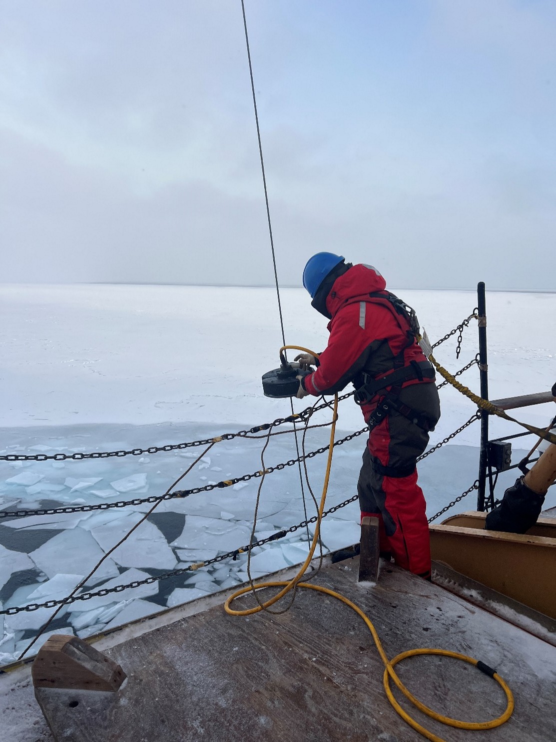 Photo 3: Céline Guéguen attaching the “chummy” to the CTD rosette wire. The chummy blows excess water off the wire as it is reeled in, preventing ice from building up on the wire block. Photo by Annabel Payne. 
