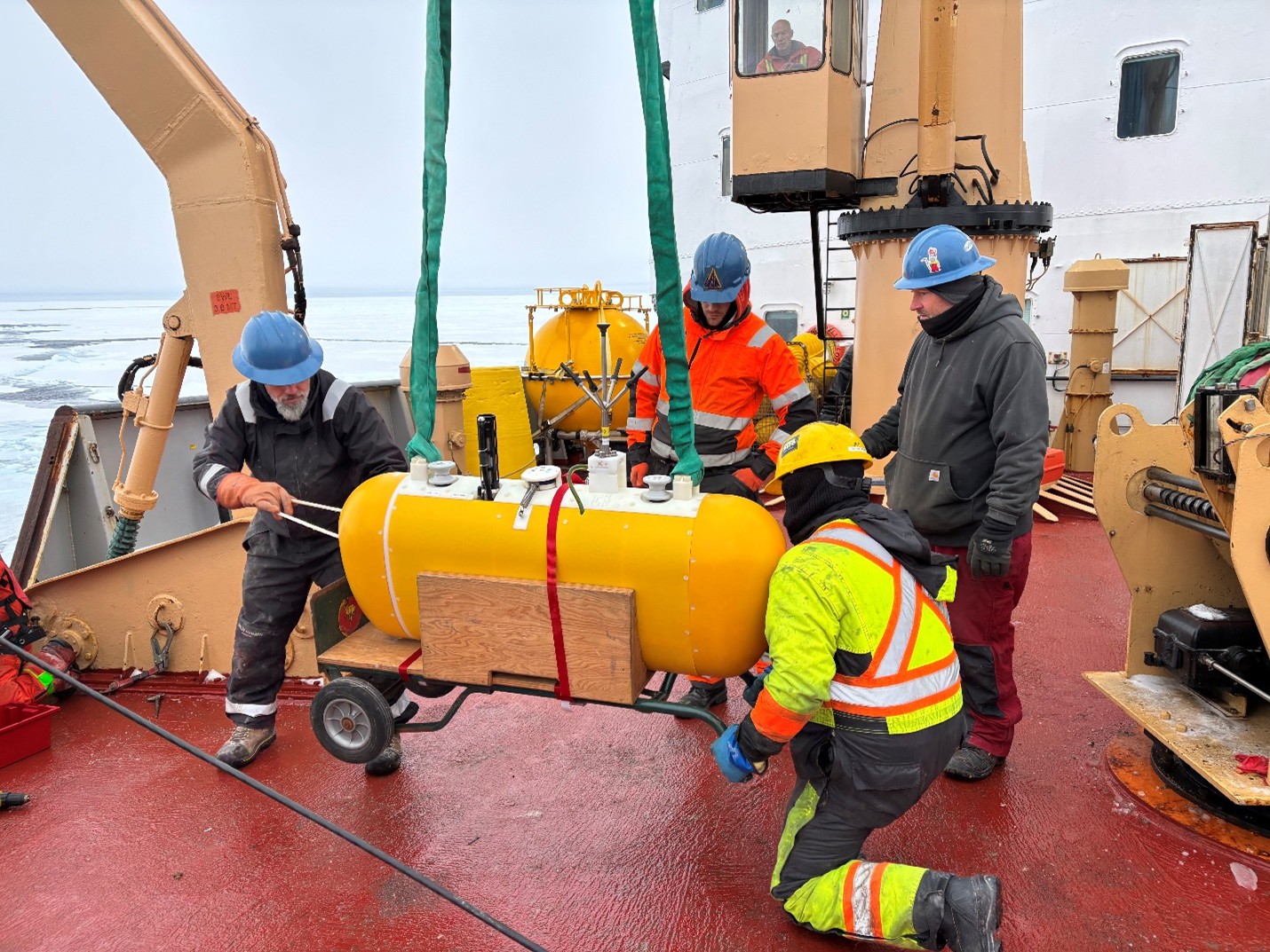 Photo 4: (left to right) Jeff O’Brien, Tim McDonough, deckhand Devon Fitzpatrick, and Cory Beatty attaching a McClane Moored Profiler (MMP) to Mooring B’s wire. Daryl Tobin is operating the crane.  