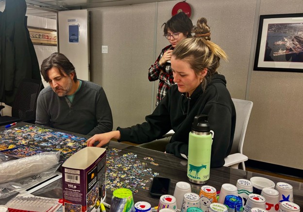 Picture8 Photo 6: (left to right) Paul Macoun, Erinn Raftery, and Paige Hagel working on a puzzle while waiting for news about a potential ice floe candidate.