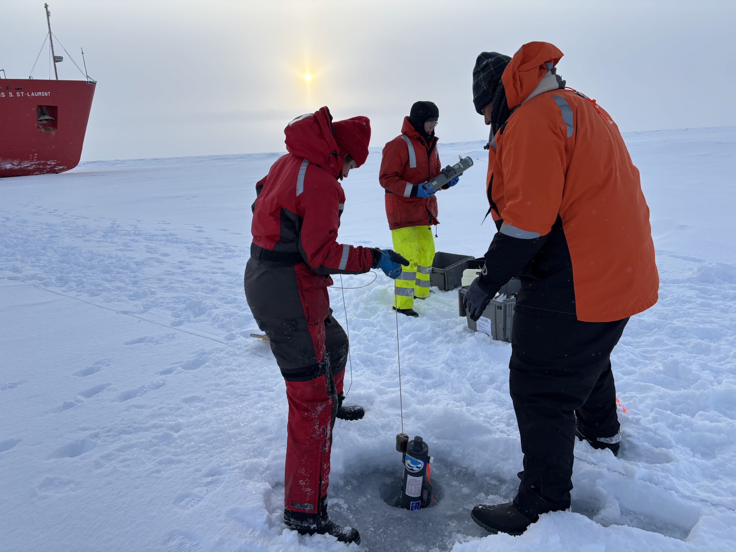 Chloe Immonen (left) and Lauren Bannerman-Maxwell (right) collecting a water sample under the ice. Photo by Jennifer Kosty. 
