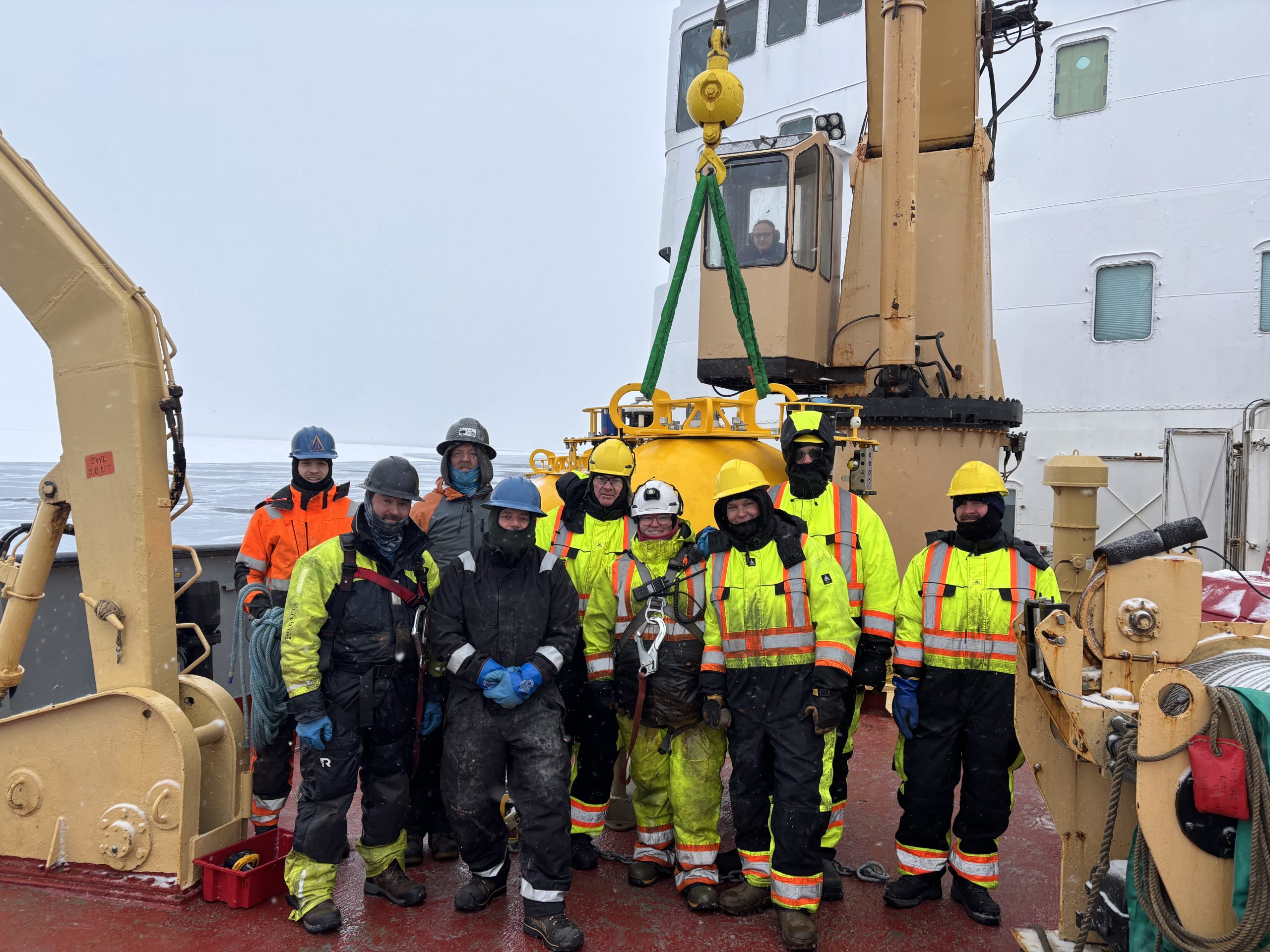 The WHOI team and deck crew posing with Mooring A’s top sphere near the end of the deployment process. Photo by Jennifer Kosty. 