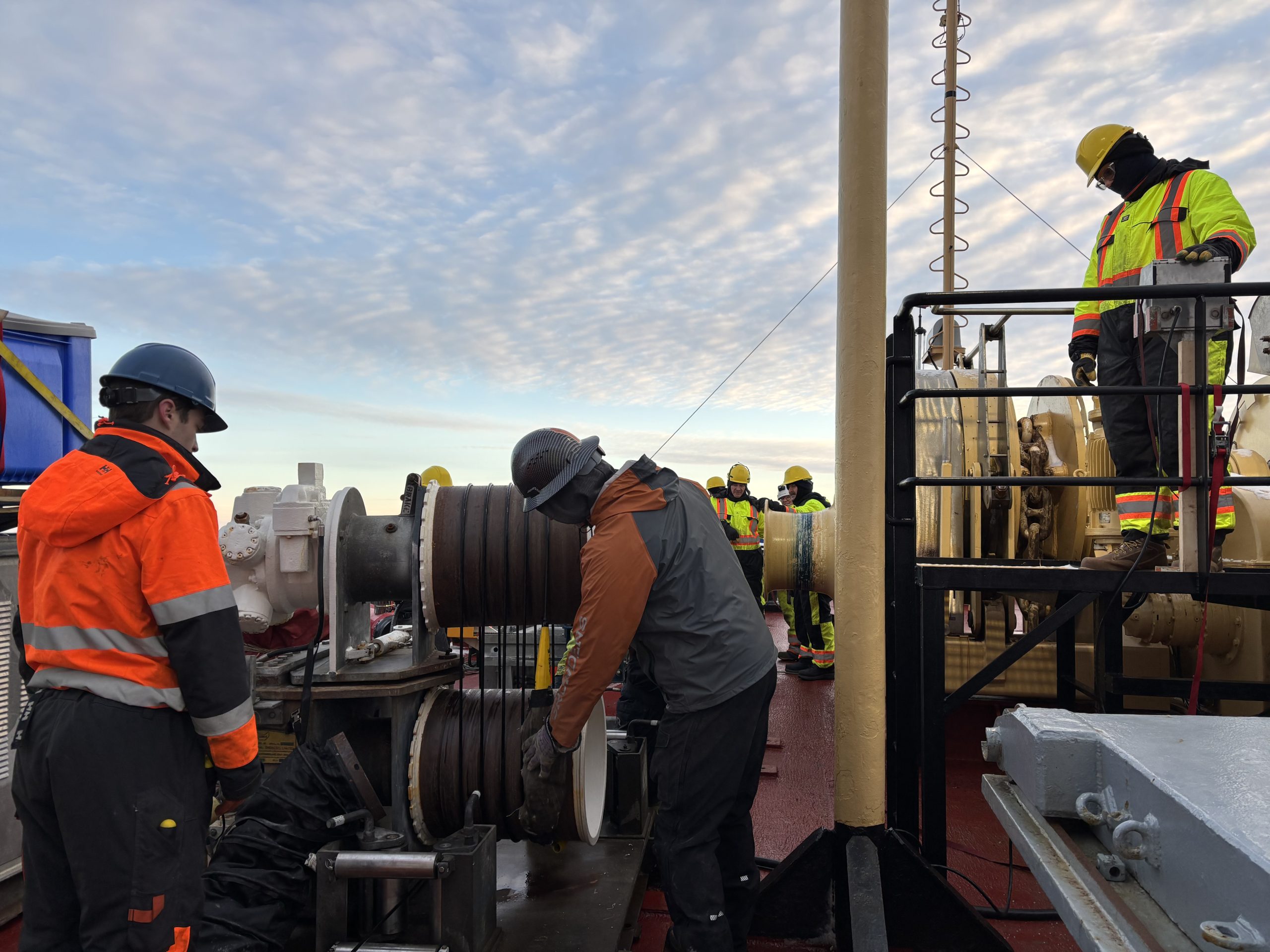 Tim McDonough (left) and Eric Hutt (right) monitoring the mooring wire as it is reeled in. Photo by Jennifer Kosty. 
