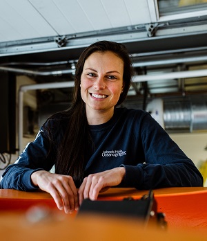 WHOI mechanical engineer, Molly Curran poses with autonomous underwater vehicle, Nereid Under Ice (NUI) in the Blake auto bays. Curran has worked with WHOI for more than six years adding crucial elements to vehicles like Nereid, including hydraulic pumps that help the vehicle's manipulator arms move during missions (Daniel Hentz, © Woods Hole Oceanographic Institution)