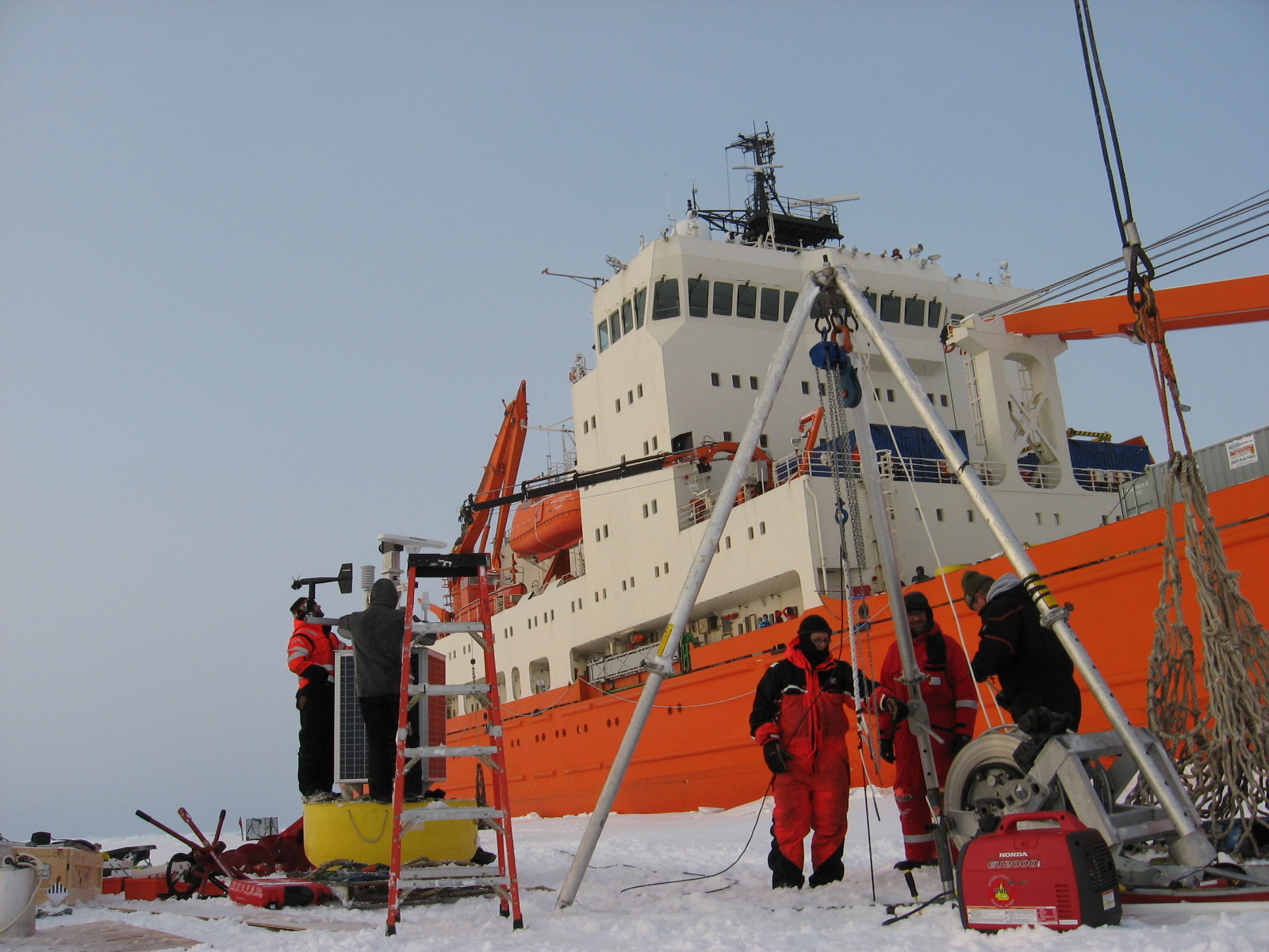 Carlton Rauschenberg and Vladimir Alexeev check the sensors on the O-buoy (left), while Dunn, Monsees and Keene transfer the ITP wire load from the winch to the tripod using a cable grip (right).  (Photo by Frank Bahr)