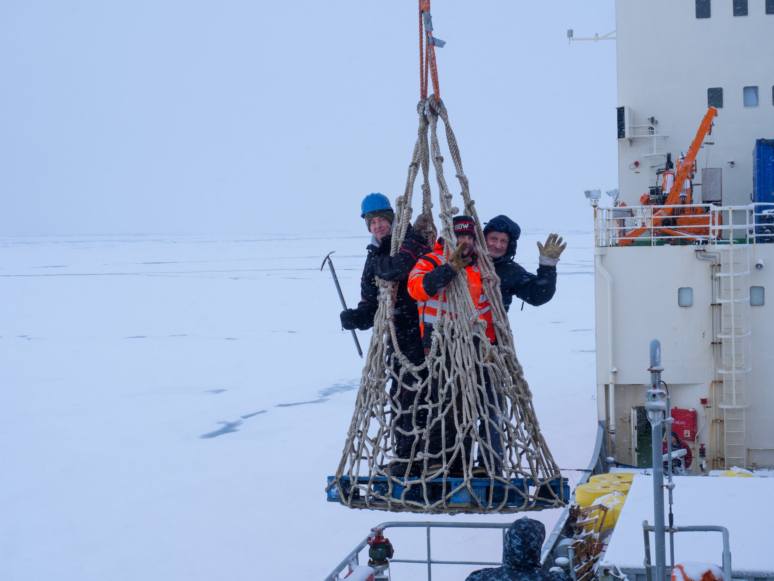 Jim Dunn, Carlton Rauschenburg, and Andrey Masanov are lowered onto the ice for the deployment operations on the pallet plane to begin the deployment operations. (Photo by Frank Bahr)