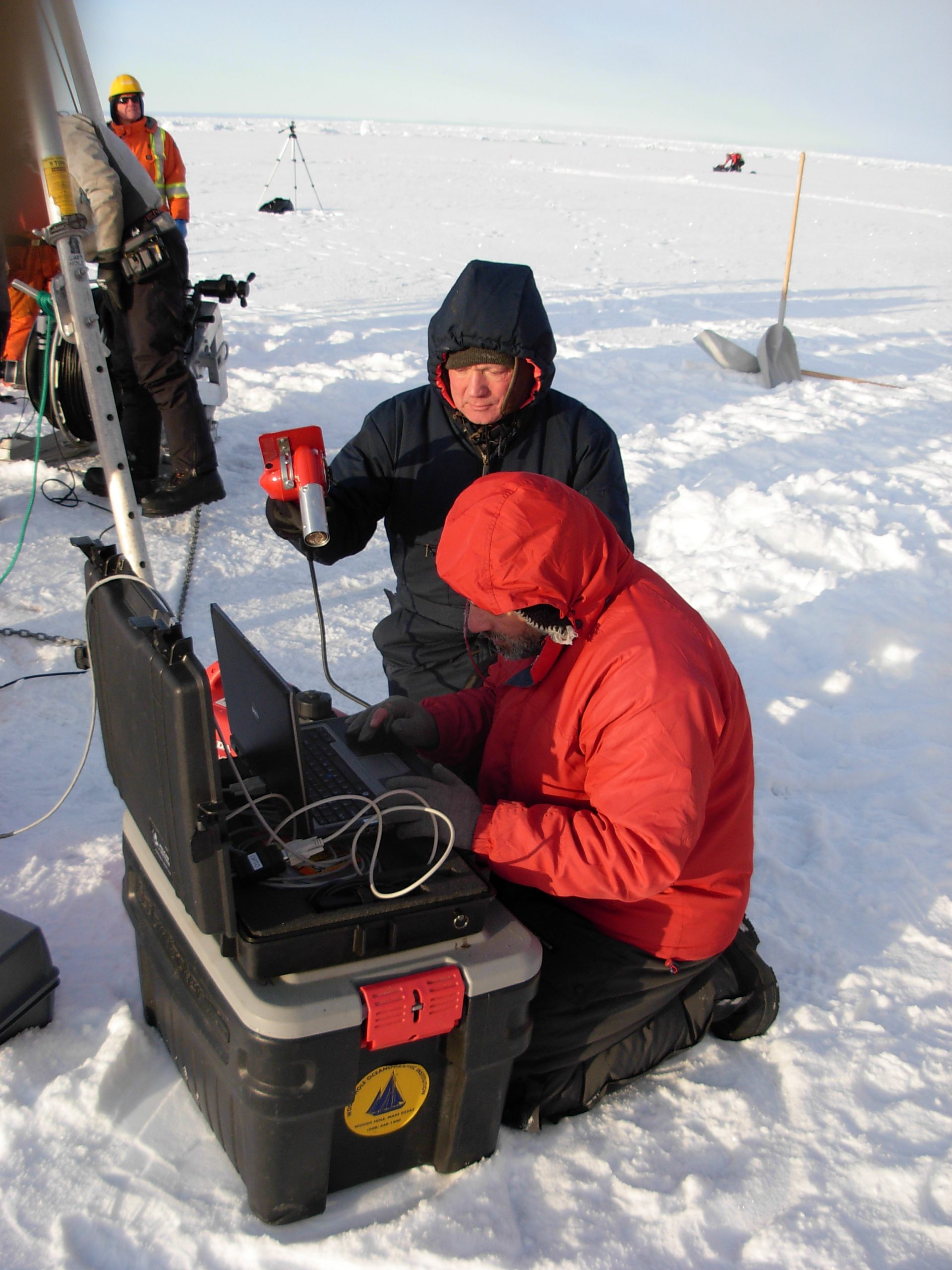 Due to the cold temperatures, Proshutinsky assists O’Brien during the profiler inductive modem test by holding a heat gun on the laptop to keep it warm. (Photo by Rick Krishfield)