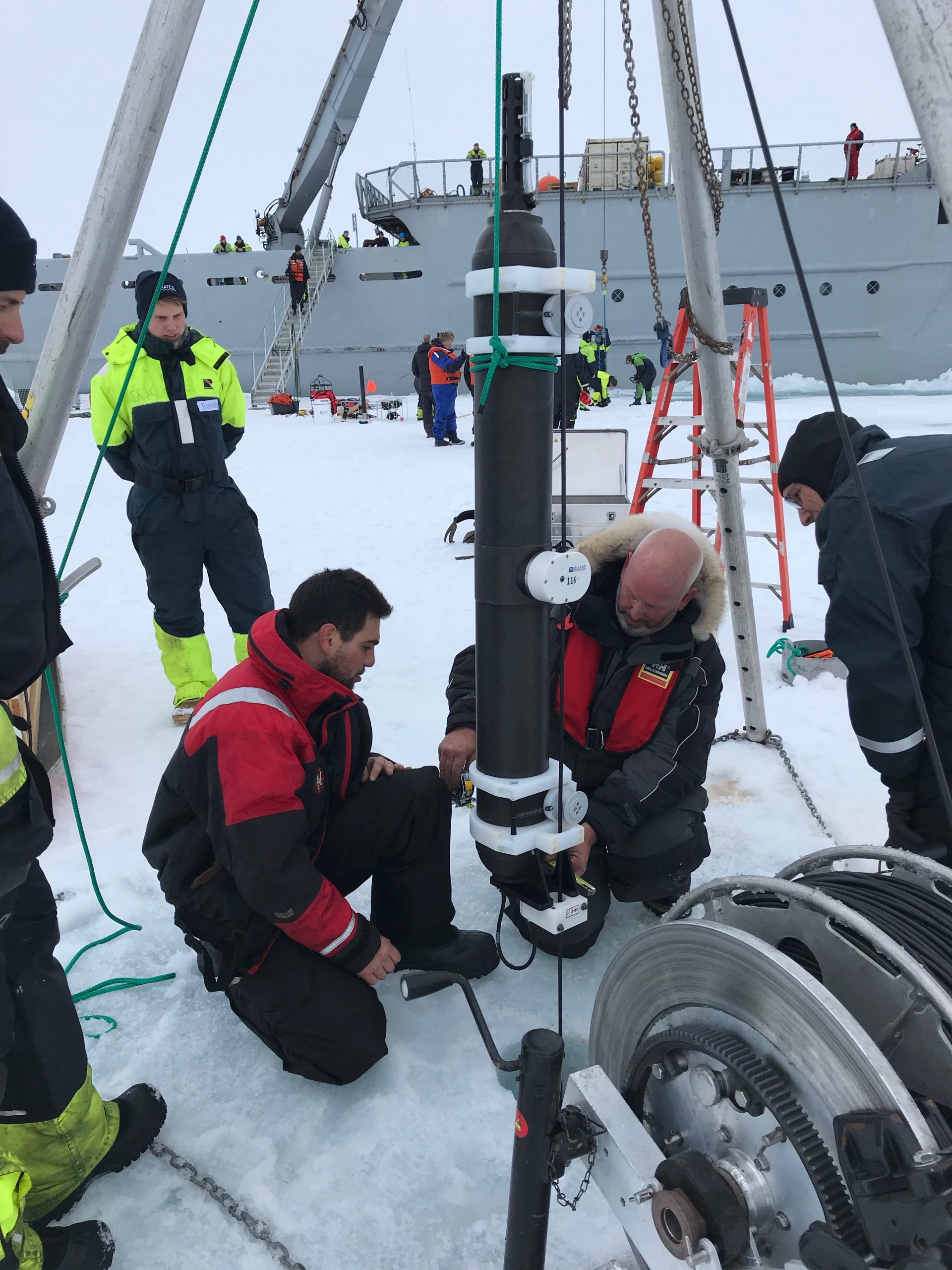 Llanos and Ryder clamp the profiler to the ITP tether just prior to lowering the instrument through the ice hole.  (Photo by Hanne Sagen)