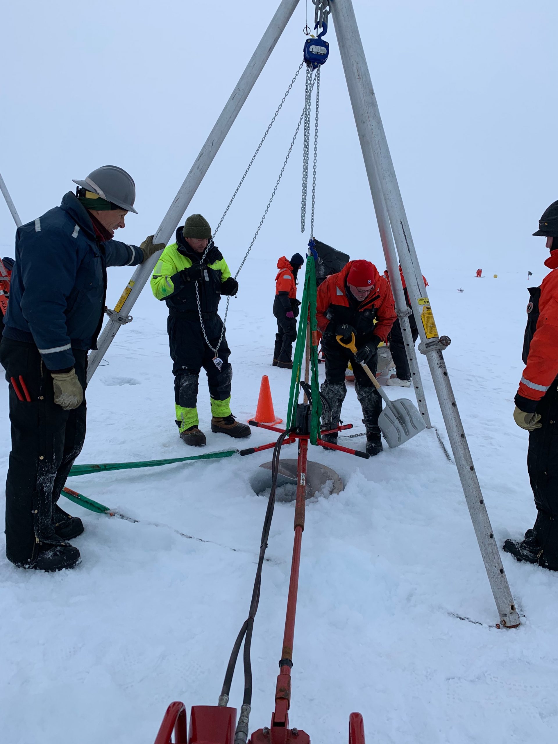 John Kemp shovels snow away from the 24” diameter auger hole through the ice floe. (Photo by Frank Bahr)