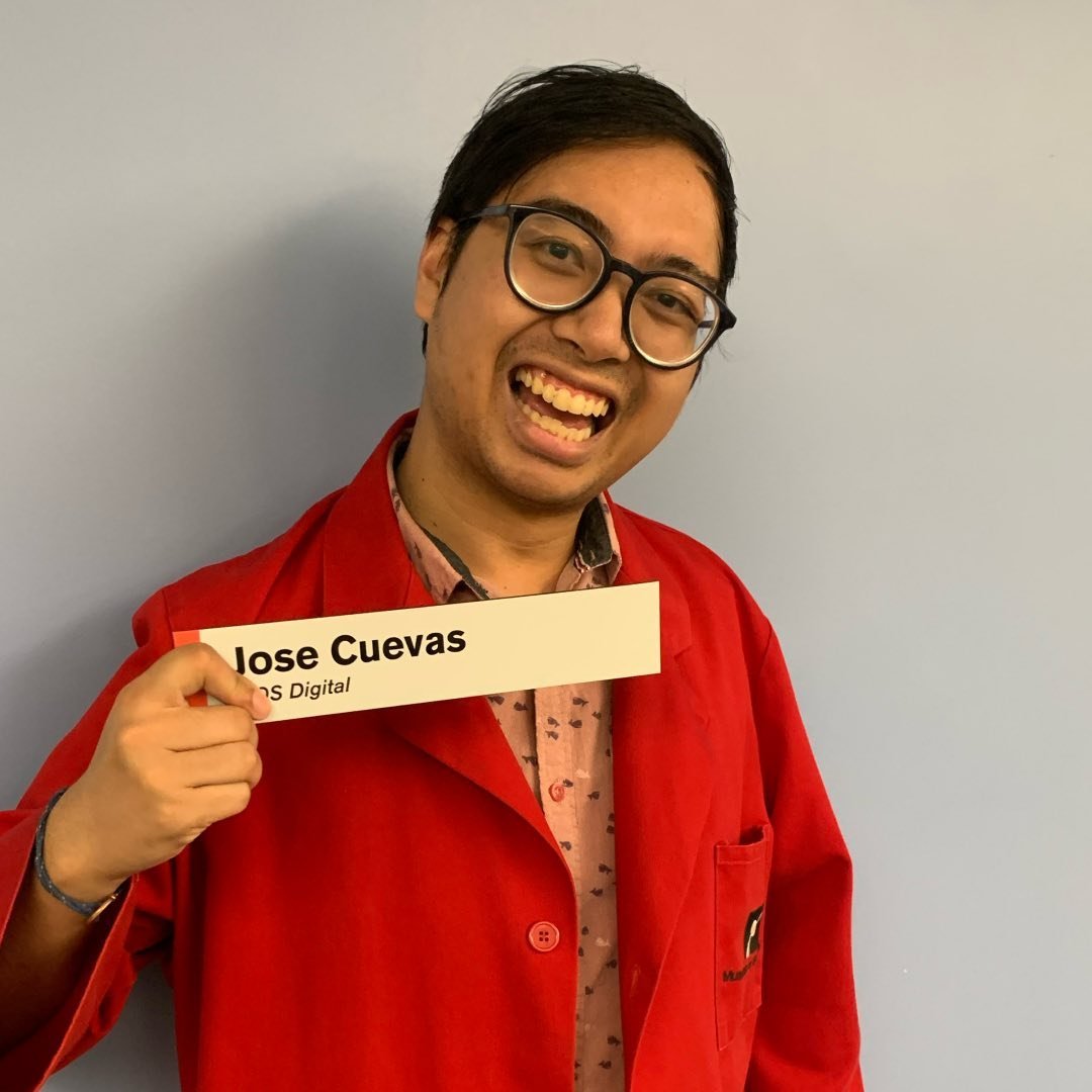 Jose Cuevas wearing a red Museum of Science lab coat, and holding a sign that says Jose Cuevas, MOS Digital