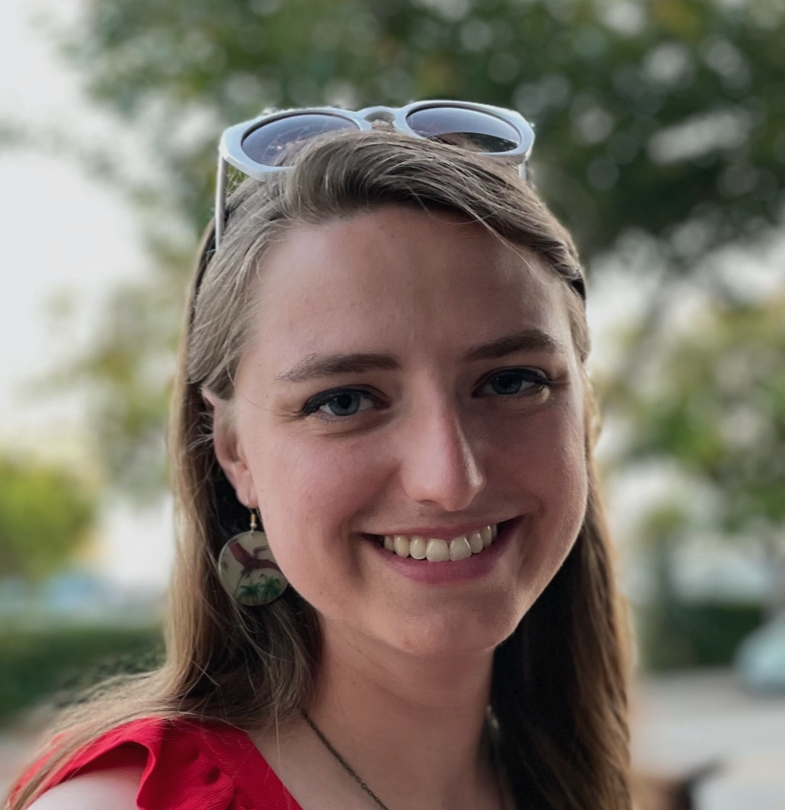 Headshot of a Monica Marion, a smiling woman wearing pterodactyl earrings