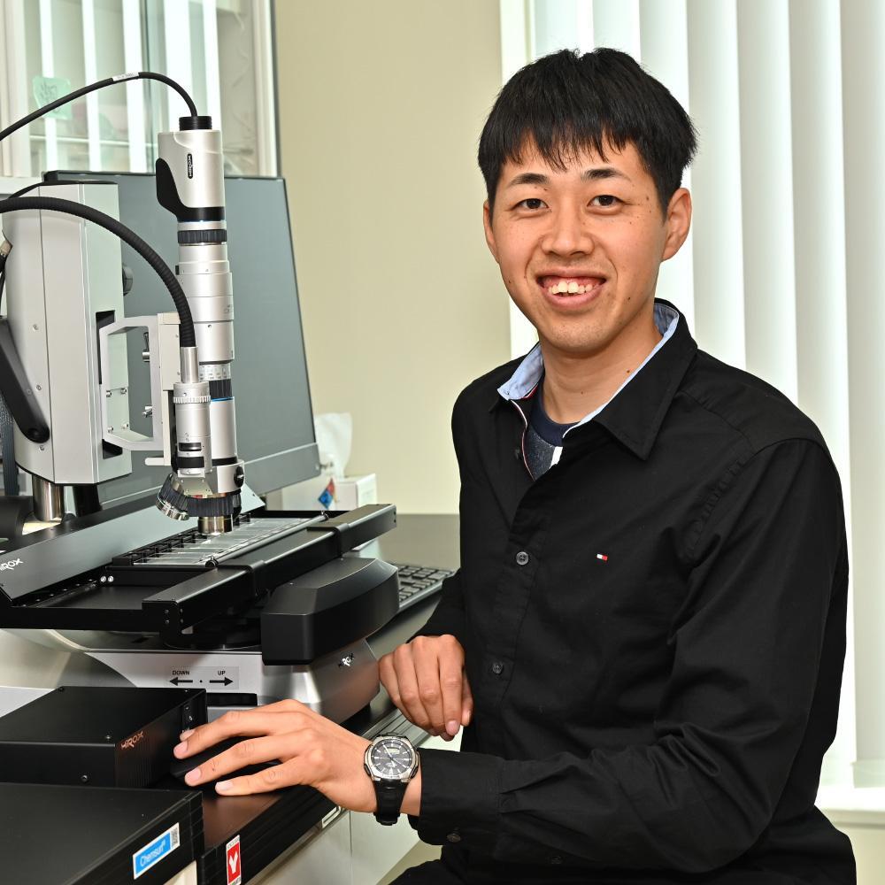 Kazuhide Mimura sitting by a microscope