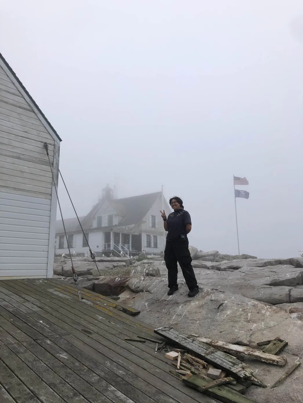 Eun-Jae, a young Korean-American man, stands on a foggy, rocky island. He is putting up a peace sign and grinning at the camera.