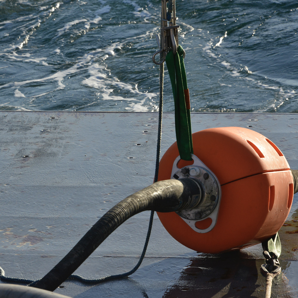 Bright orange floats are connected to the Near Surface Instrument and the buoy with black stretch hoses.  The stretchiness of the hoses is key to allow everything attached to the mooring the flexibility to move with the water.  The floats weigh about 300 lbs. and greatly aid the stability of the mooring. 
