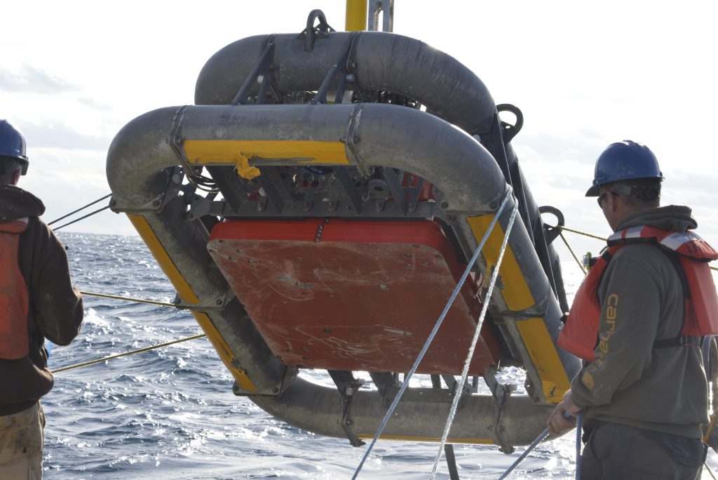 A multi-function node is the last component of the array to go into the water.  It is equipped with multiple instruments, and receives power from the buoy at the surface. The orange interior square seen in the center of the MFN is the anchor to keep the mooring in place. 